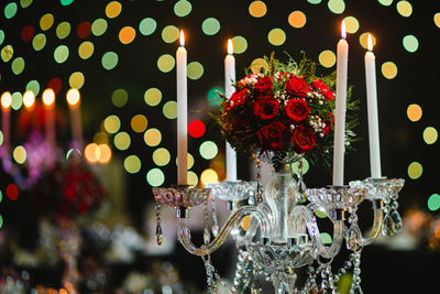 Close-up of candlestick holder with roses during christmas at night