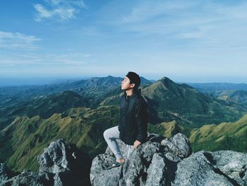Woman sitting on rock against mountains