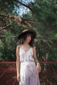 Young woman wearing hat standing against trees