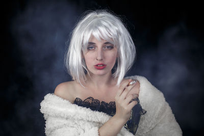 Portrait of female model smoking against black background