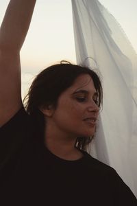 Portrait of young woman standing against sky