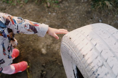 Low section of baby girl touching white tire on field