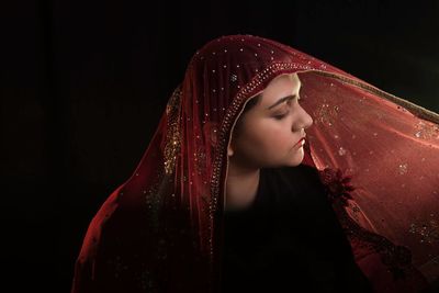 Young woman holding sari against black background