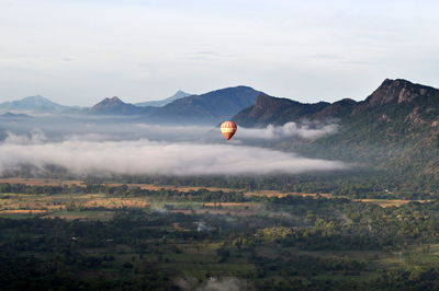 Hot air balloon flying over mountain against sky