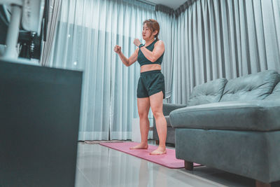 Full length of woman standing on sofa