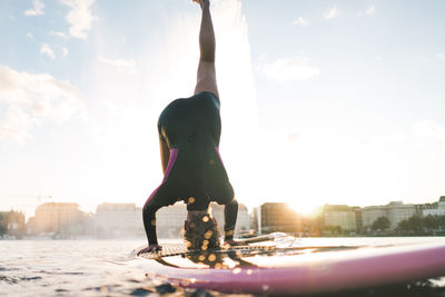 Full length of woman with arms raised against sky