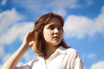 Portrait of beautiful young woman against sky