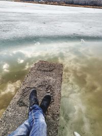 Low section of man standing on lake