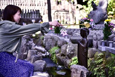 Side view of woman standing by purple flowering plants