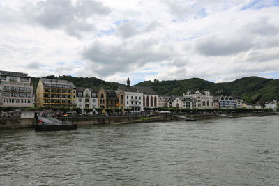 Scenic view of river by buildings against sky