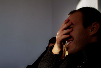 Close-up of young man covering face with hand