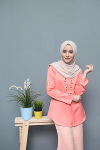 Portrait of smiling young woman standing against white background