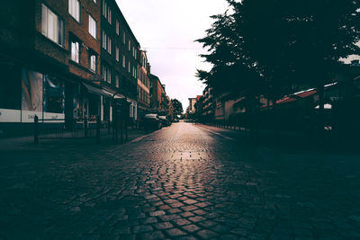 Wet street amidst buildings in city