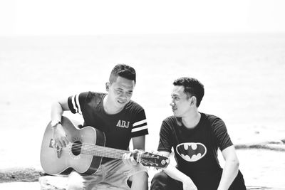 Young man playing guitar on beach