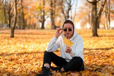 Man wearing sunglasses sitting on street during autumn