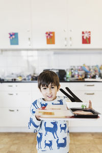 Portrait of happy boy carrying food tray