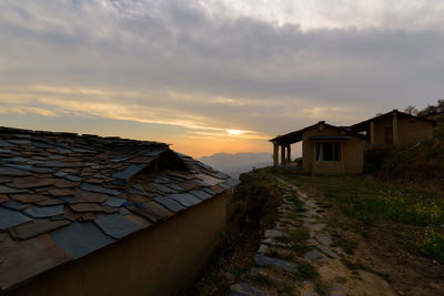 Houses by road against sky during sunset