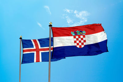 Low angle view of flag flags against blue sky
