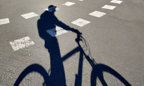 Shadow of person riding bicycle on road