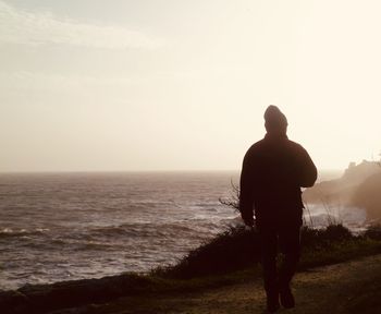 Rear view of man looking at sea against sky