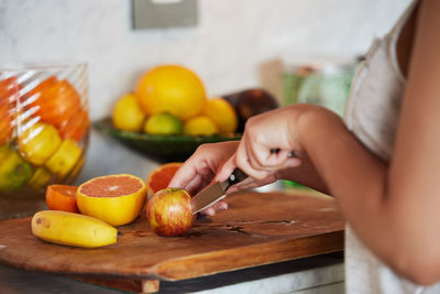 Midsection of woman holding fruit on table