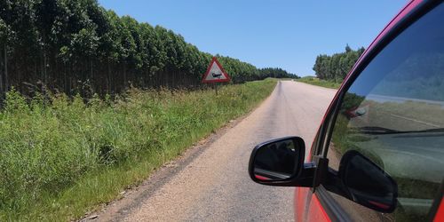 Car on road amidst field against sky