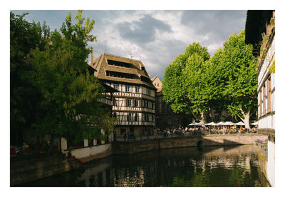 Buildings by river against sky