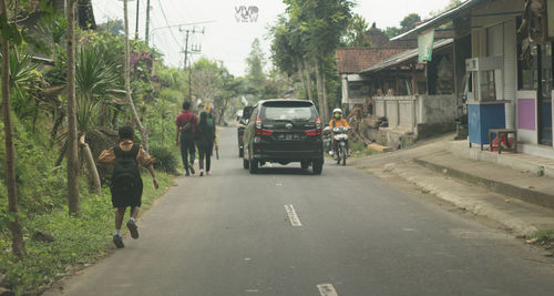 Rear view of people walking on road in city