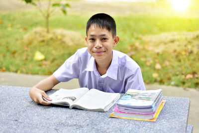 Boy reading book while sitting at park