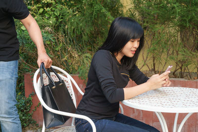 Young woman using mobile phone while sitting in park