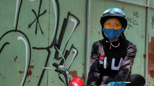 Portrait of man standing against graffiti wall