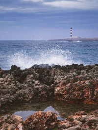 Lighthouse by sea against sky