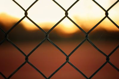 Full frame shot of chainlink fence against sky during sunset