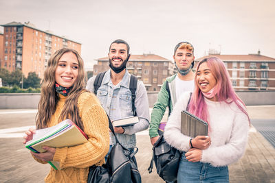 Smiling friends standing on street against building