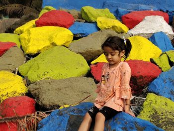 Full length of woman sitting against multi colored wall