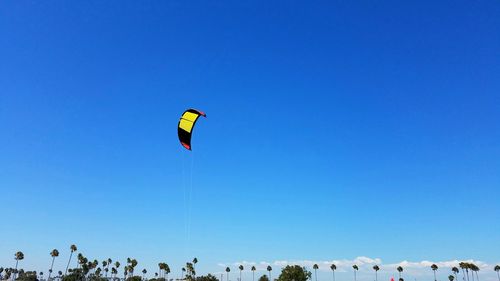 People paragliding against clear blue sky