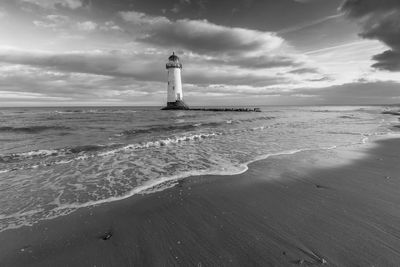 Lighthouse by sea against sky