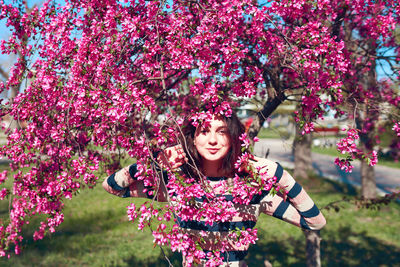 Woman with pink flowers against tree