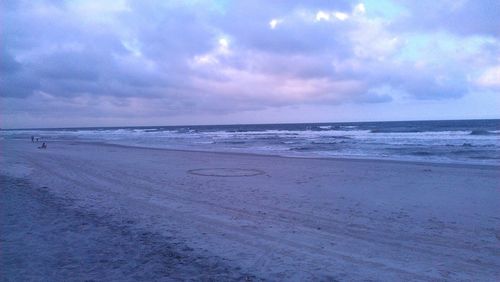 Scenic view of beach against cloudy sky