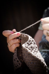 Cropped hand woman knitting while sitting at home