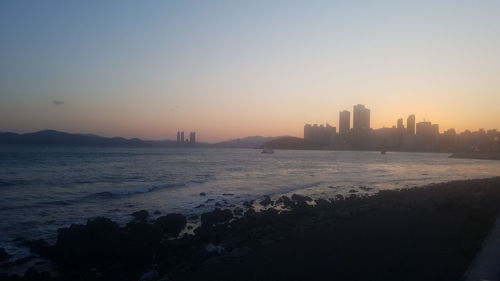 Scenic view of sea and buildings against clear sky