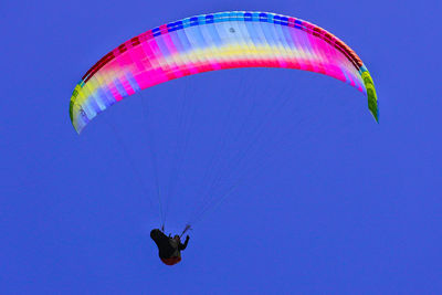 Low angle view of person paragliding against clear sky