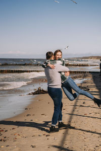 Close up of couple kissing and hugging near the sea and looking to each other.