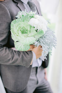 Midsection of man holding flower bouquet