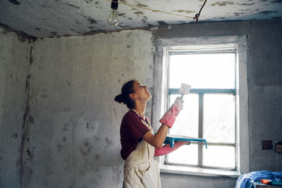 Side view of woman working on window