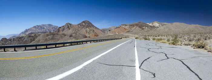 Road by mountain against clear blue sky