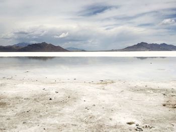 Scenic view of beach against cloudy sky