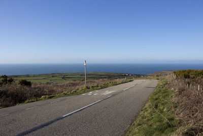 Road by sea against clear sky