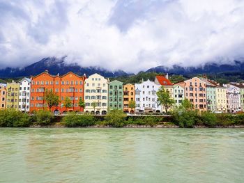 Buildings by river against sky in city