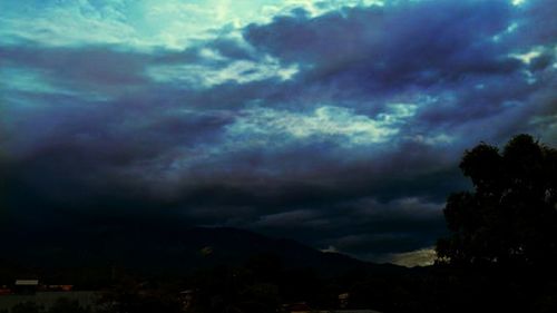 Silhouette of trees against dramatic sky